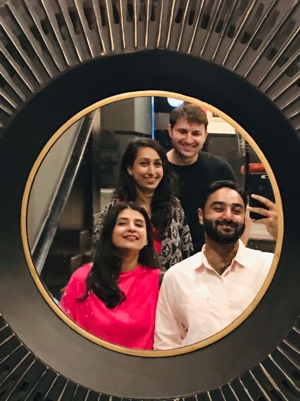 Ahmed Qureshi and friends reflected in a round mirror.