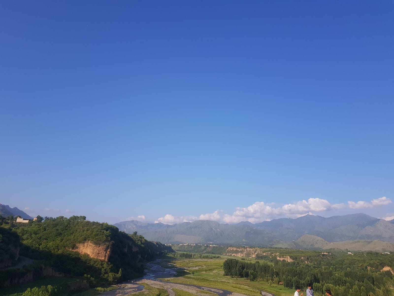 A wide mountain landscape under a clear blue sky.